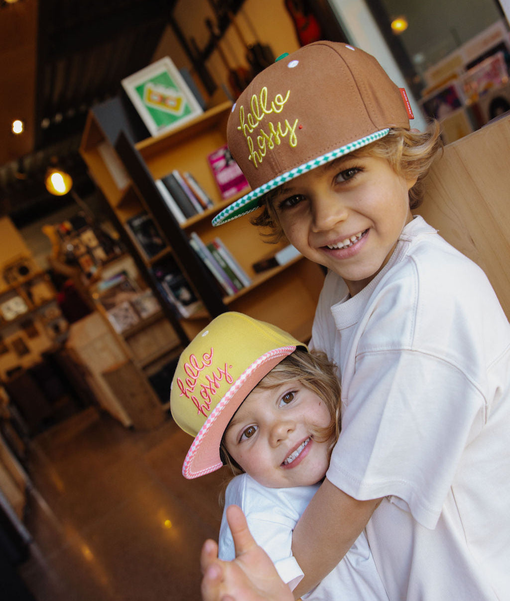 Cappellino da bambino marrone con visiera piatta e ricamo Hello Hossy e cappellino giallo con visiera rosa Hello Hossy