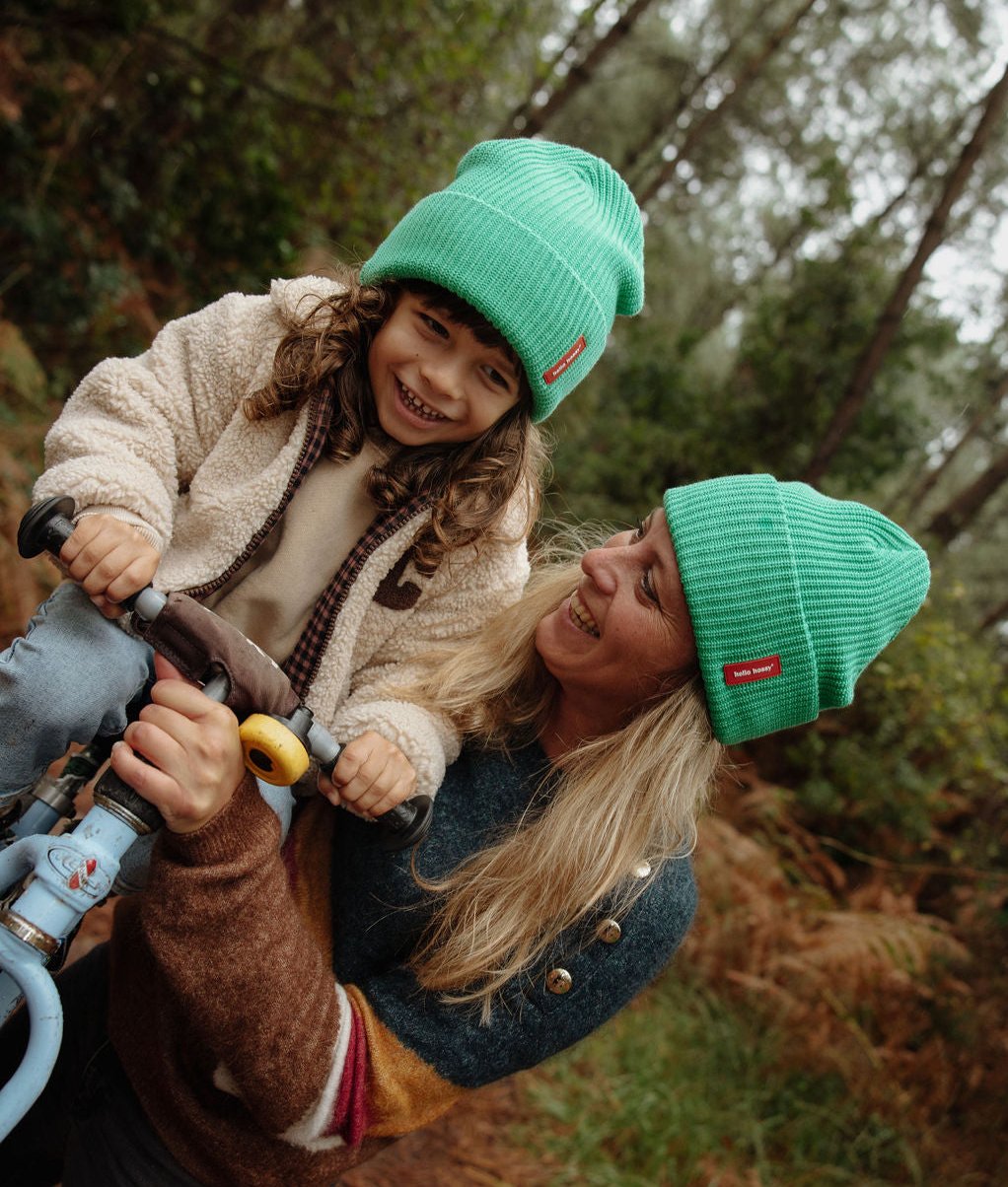 Berretto verde per bambini con etichetta rossa, indossato in duo con mamma Hello Hossy