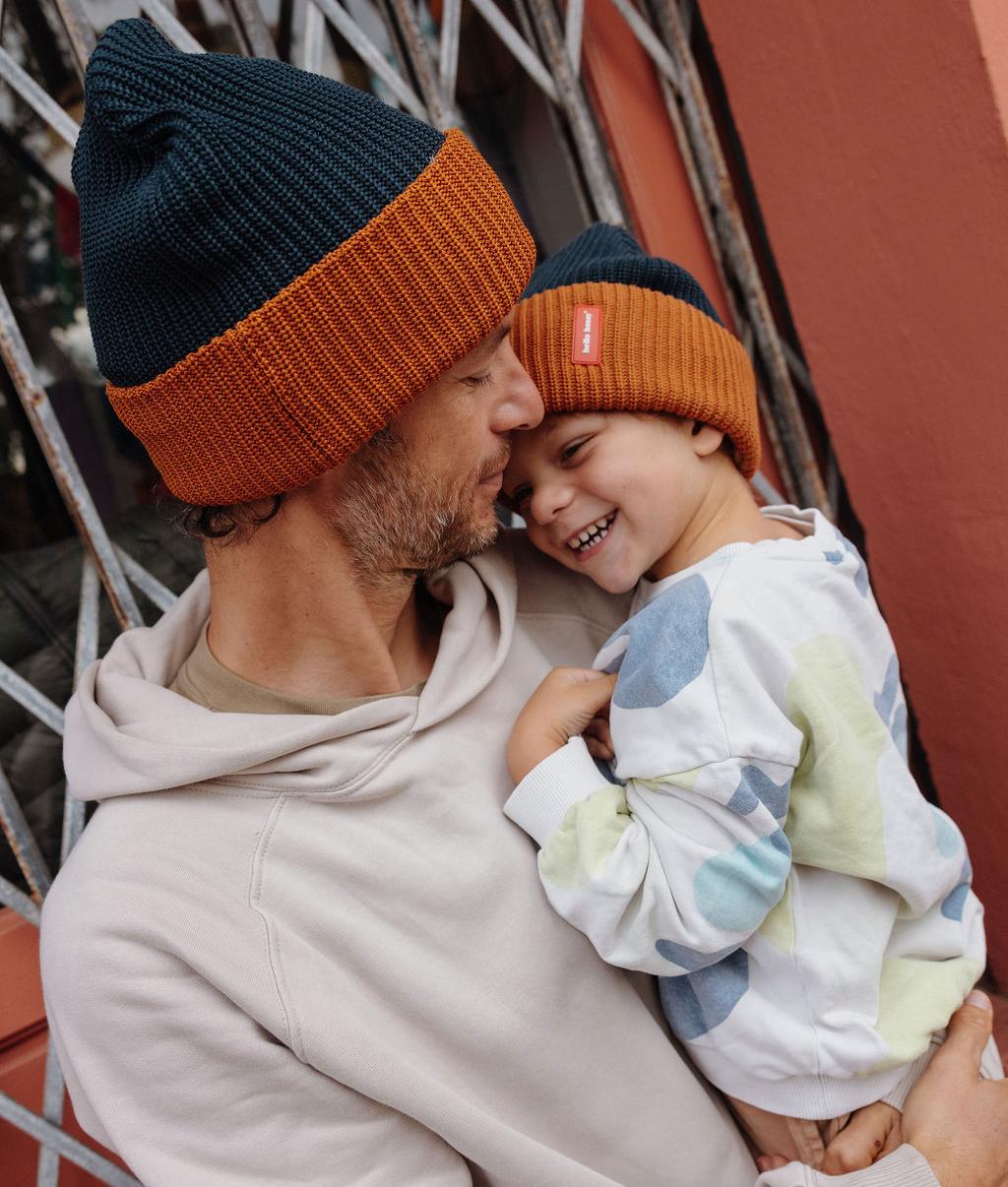 Berretto in maglia bicolore indossato da un papà e suo figlio che tiene in braccio - vista di profilo - Hello Hossy