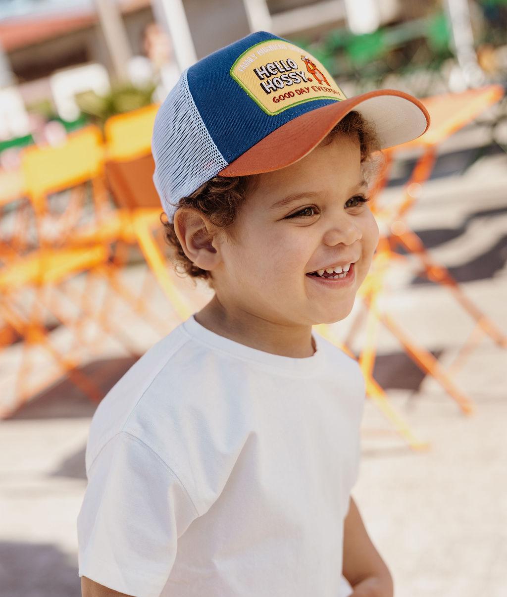 Bambino con cappellino blu e arancione, rete bianca, patch Hello Hossy