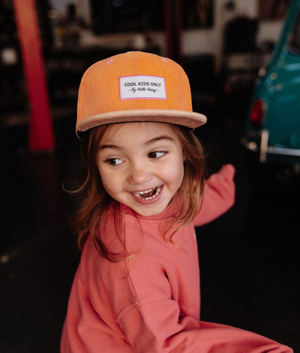 Bambina di fronte che indossa il cappellino in velluto arancione Sweet Mandarine – foto lifestyle – Hello Hossy
