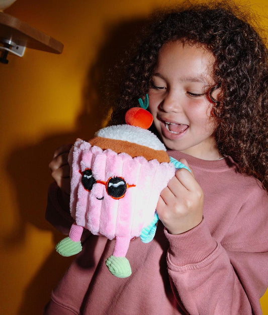 Bambino che tiene il peluche morbido a forma di torta Cherry Cake dai manici del suo zaino - foto lifestyle - Hello Hossy