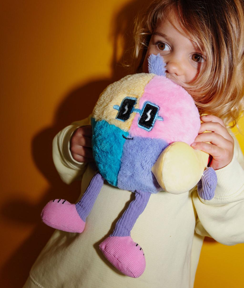 Bambina in piedi che stringe a sé il peluche originale Disco Pop - vista a 3/4 - Hello Hossy