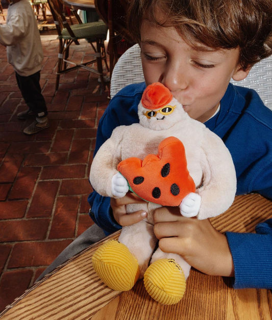 Bambino che abbraccia il morbido Peluche a forma di yeti Frosty Yeti appoggiato su un tavolo in terrazza - foto lifestyle - Hello Hossy