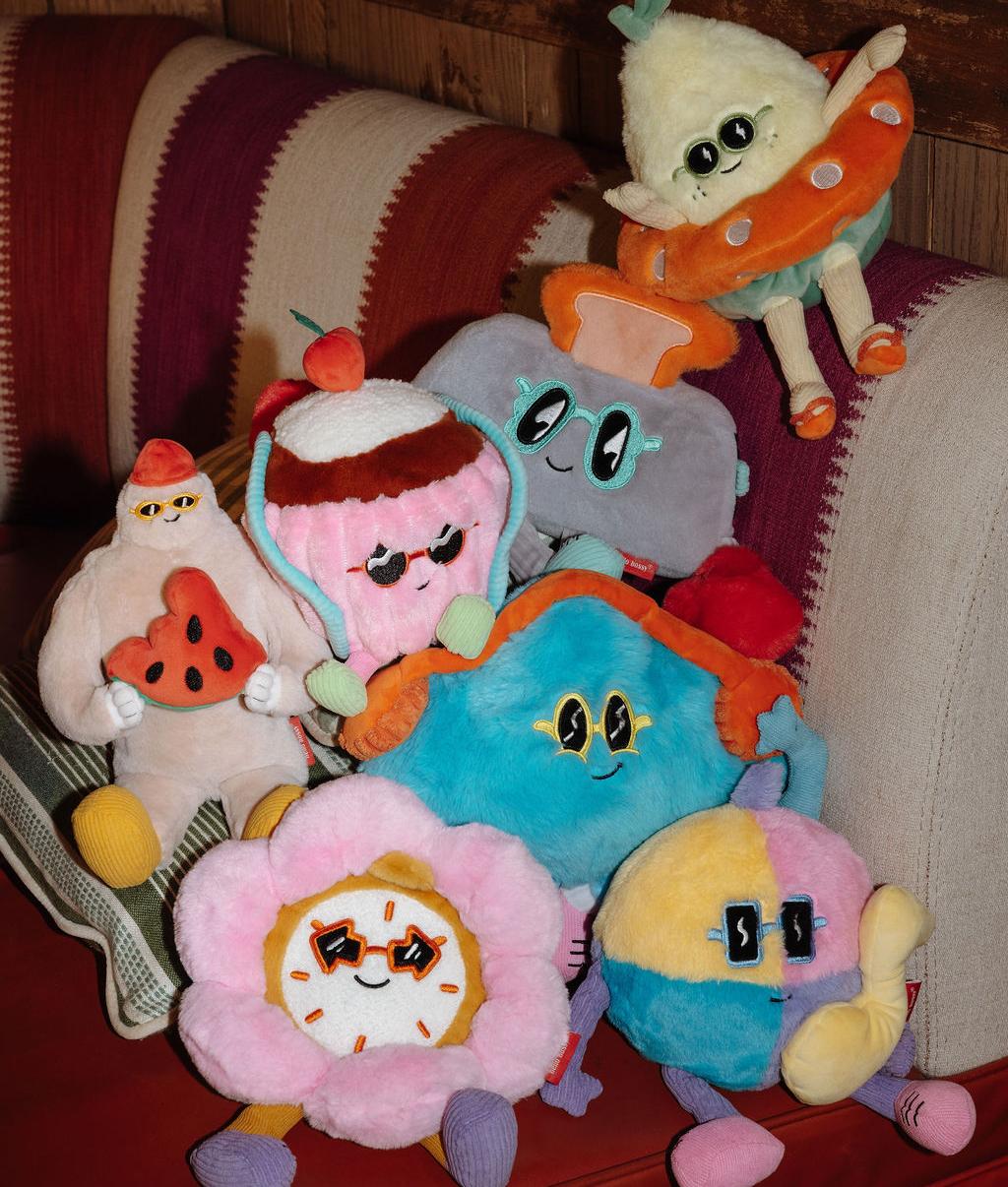 Collezione di peluche Hello Hossy impilati su un divano - foto d'atmosfera