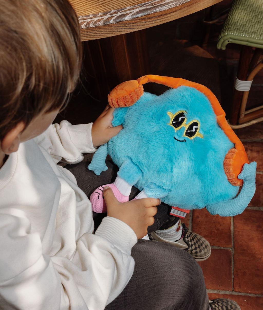 Peluche originale a forma di nuvola con cuffie da musica, Rock N Cloud, tenuto da un bambino – vista dall'alto – Hello Hossy