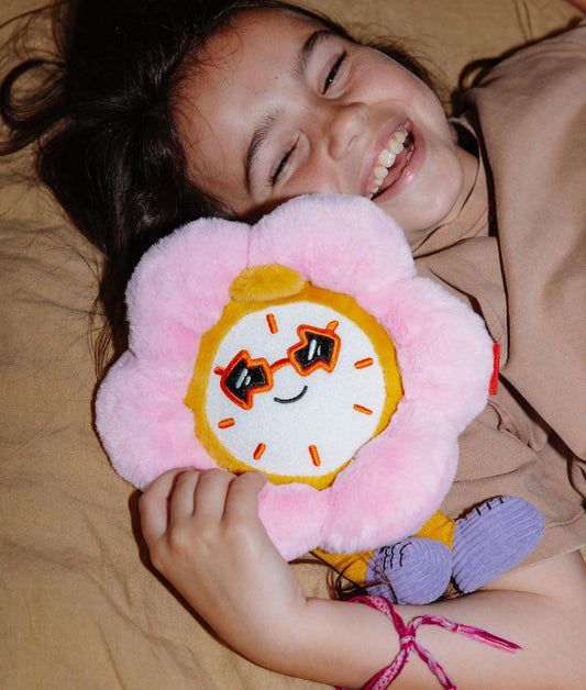 Bambina sdraiata che stringe a sé il Peluche a forma di fiore-orologio Tic Tac Bloom - foto lifestyle - Hello Hossy