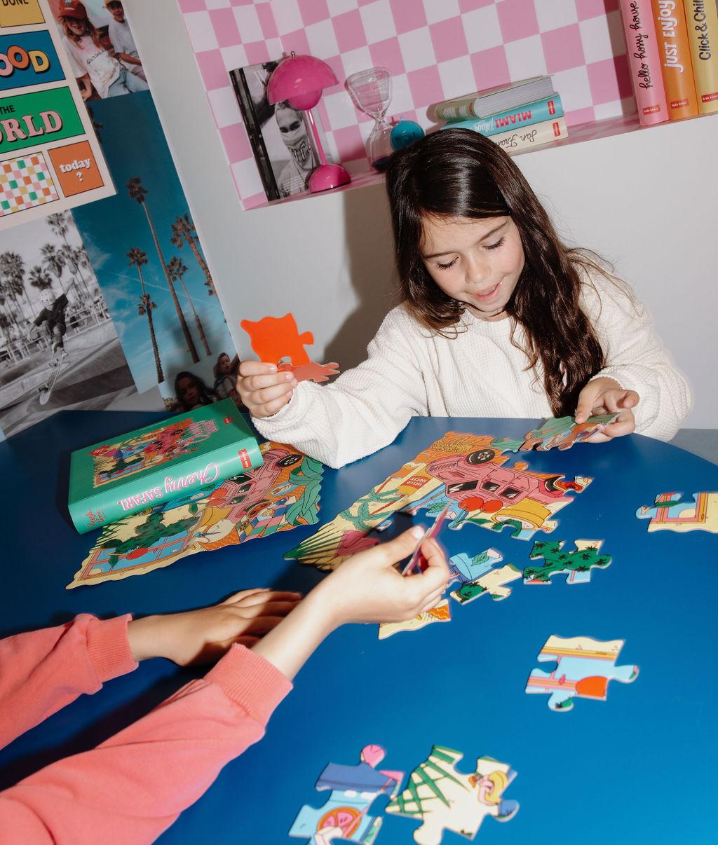 Bambini che assemblano il puzzle colorato da 25 pezzi "Cherry Safari" su un tavolo – foto lifestyle – Hello Hossy