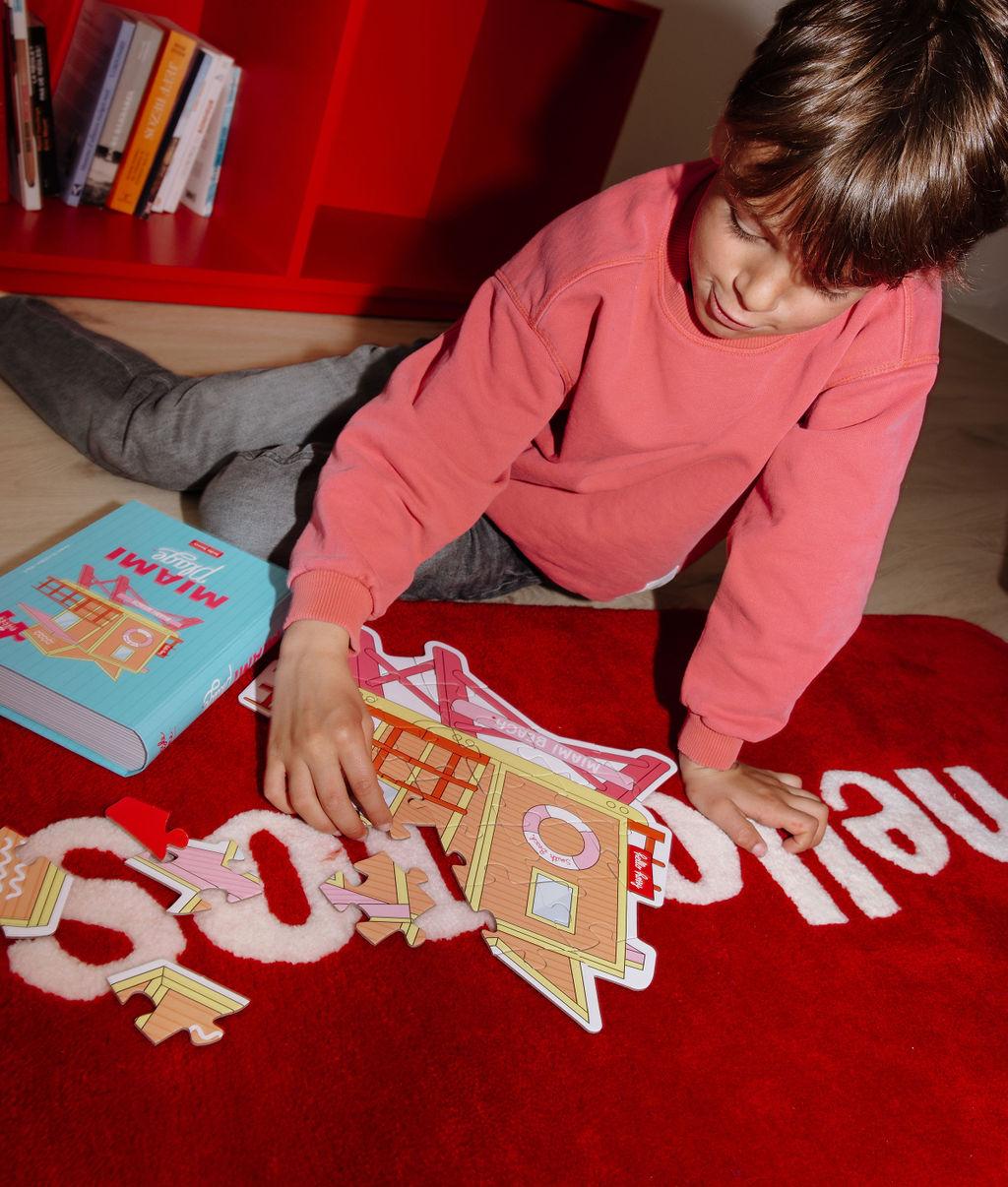 Bambino che assembla il Puzzle colorato da 28 pezzi "Miami Plage" su un tappeto a terra – foto lifestyle – Hello Hossy